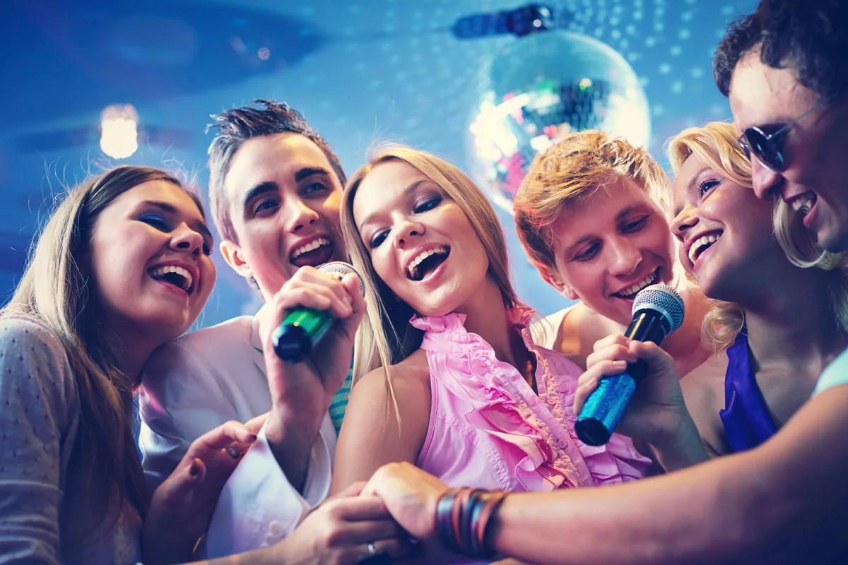 Grupo de amigos cantando karaoke y riendo